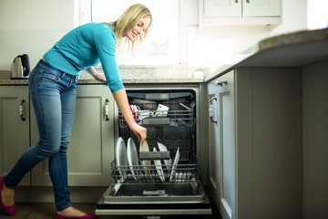 Pretty blonde woman emptying the dishwasher