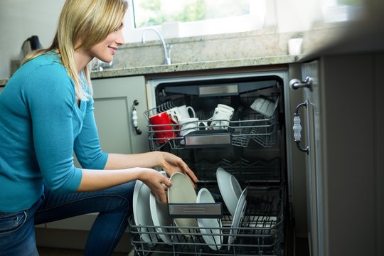 Pretty Blonde Woman Emptying The Dishwasher