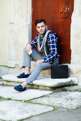 Stylish man sitting on the stairs near wooden doors