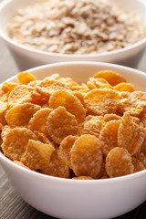 Cornflakes and oatmeal in white bowls vertical