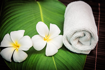 spa concept. white towel and plumeria flowers on the bamboo mat