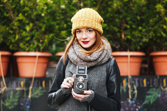 Cute girl with red lips standing outdoor holding camera