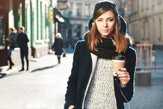 Cute girl with brown hair holding coffee on the street