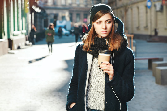 Cute girl with brown hair holding coffee on the street
