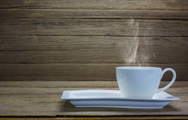 White coffee cup with smoke on wood background