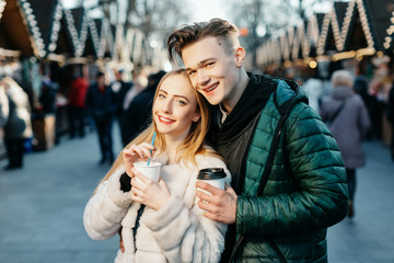 Fototapeta premium Atrakcyjna para stojących razem na Jarmark Bożonarodzeniowy