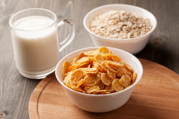 Oatmeal, cornflakes and glass of milk on wooden table