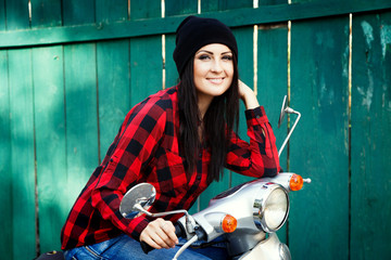 Naklejka premium Attractive cheerful girl, sitting on vintage scooter