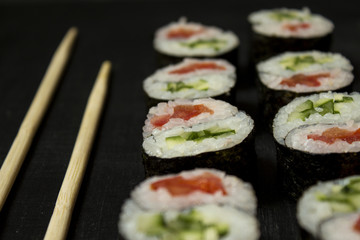 Rolls Yin-Yang vegetable with cucumber and tomato on black background