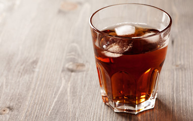 Cold drink with ice in glass on wooden table, selective focus