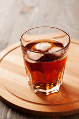Cold drink with ice in glass on wooden table, selective focus