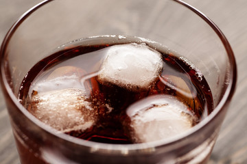 Cold drink with ice in glass on wooden table, selective focus