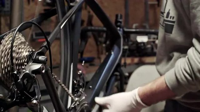 Mechanic repairing bicycle in workshop. Slider shoot