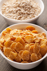Cornflakes and oatmeal in white bowls vertical