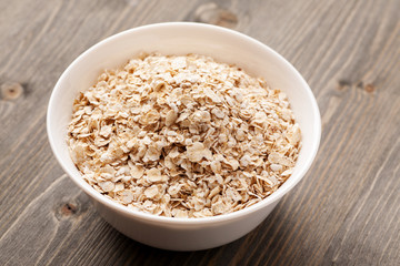 Oatmeal in white ceramic bowl on wooden table