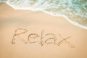 Relax message hand writing on the sand beach