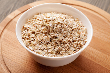 Oatmeal in white ceramic bowl on wooden board