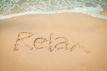 Relax message hand writing on the sand beach