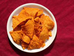 Fast food, junk-food/close up of corn nachos in plate on red background.