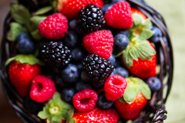 Fototapeta na wymiar Mix of fresh berries in a basket on rustic wooden background