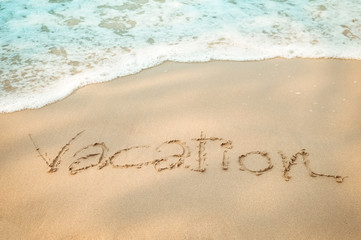 Vacation message hand writing on the sand beach