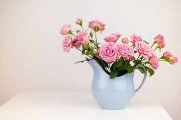 Fototapeta na wymiar Pink flowers in blue jug. Roses in jug.