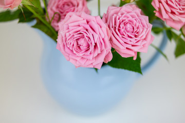 Pink flowers in blue jug. Roses in jug.