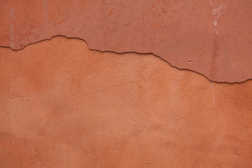 Fototapeta premium Old terracotta painted stucco wall with cracked plaster. Backgro