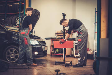 Fototapeta na wymiar Professional car mechanics inspecting headlight lamp of automobi