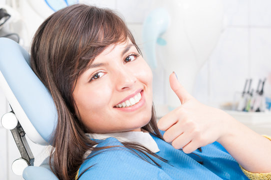 Closeup of brunette female patient smiling and showing thumb up