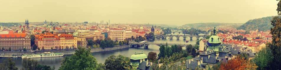 Panoramic view of old beautiful Prague city with red roofs and bridges through the river Vltava,...