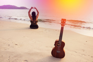 Beach, sun, sea and sand and woman with ukulele / Ukulele on beach, sun, sea and sand with woman sit and turn back hand of heart shape
