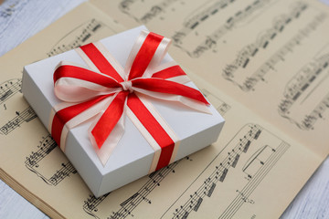 gift with red bow lying on sheet music