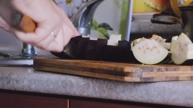 Chef on a chopping board cut the eggplant