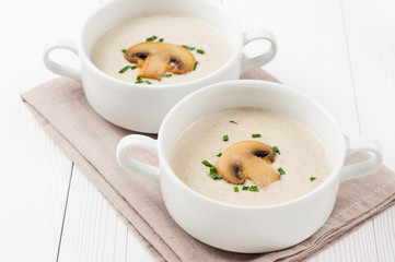 Two bowls of  mushroom cream soup on wooden boards