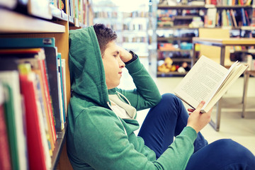 student boy or young man reading book in library
