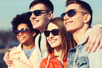 happy teenage friends in shades hugging outdoors