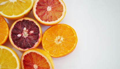 Ruby red blood oranges, navel oranges, and clementines cut in half on a white platter