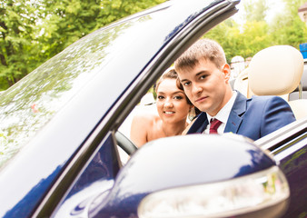 Beautiful young couple bride and groom posing in cabriolet 