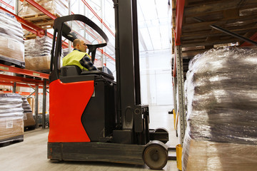 man on forklift loading cargo at warehouse