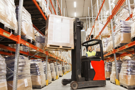 man on forklift loading cargo at warehouse