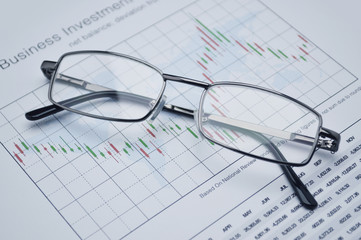 Naklejka na ściany i meble Glasses on stock market graph, financial concept