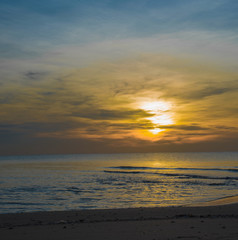 Sun sets over horizon of ocean. Sky, water and shore in the even