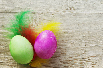 Easter eggs on wooden background. Two Easter eggs with bright feathers