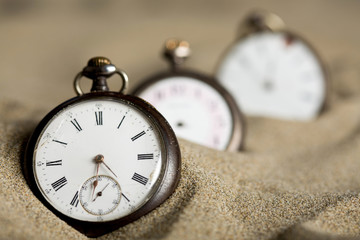 Trois vieilles montres alignées dans le sable