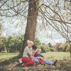 Young family is sitting under a tree