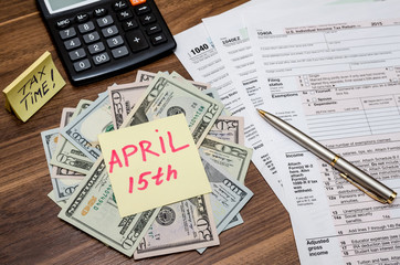 Obraz premium 1040 tax form with sticky note of april 15, us dollar and calculator