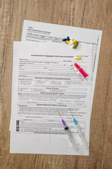 Medical patient form with pills and  syringes on  table