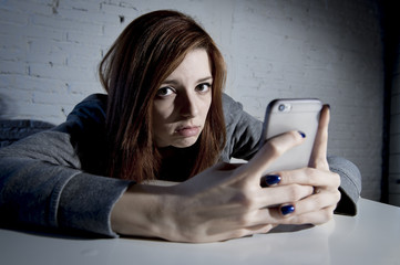 young sad vulnerable girl using mobile phone scared and desperate suffering online abuse cyberbullying