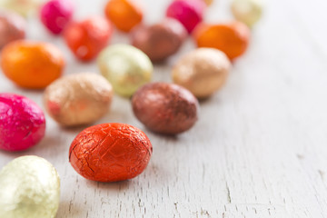 Small chocolate Easter eggs on a rustic white background